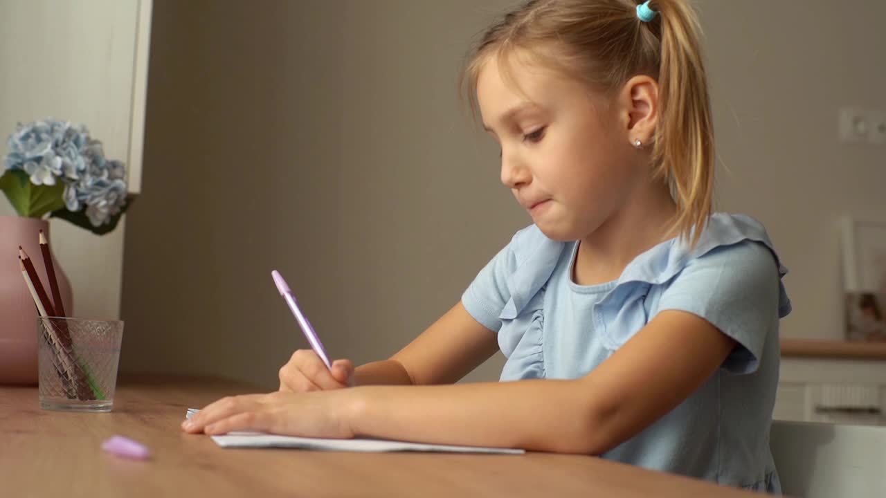 近距离的思考漂亮的小学女孩学习写作做作业坐在家里的桌子靠窗。视频素材