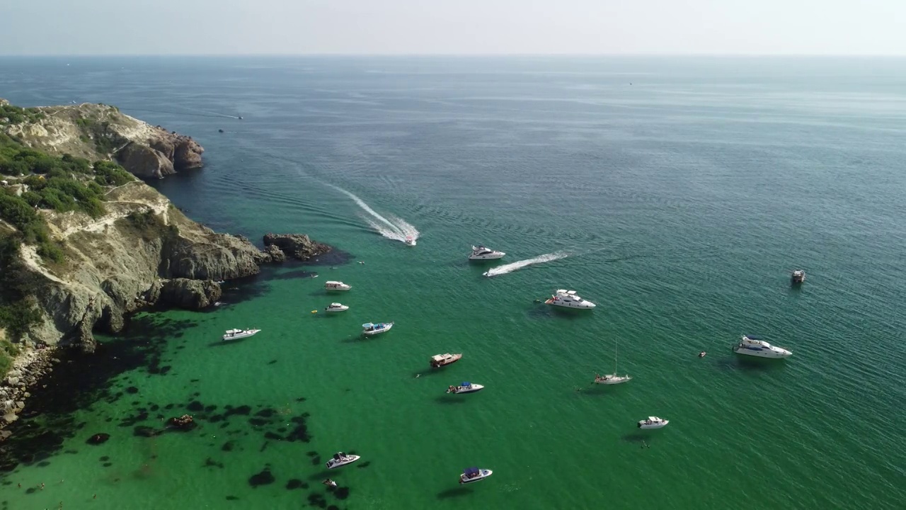 空中全景海景与湛蓝的大海和岩石海岸。在岩石的背景下，美丽的泻湖上的游艇。是夏季旅游和度假的理想目的地视频素材