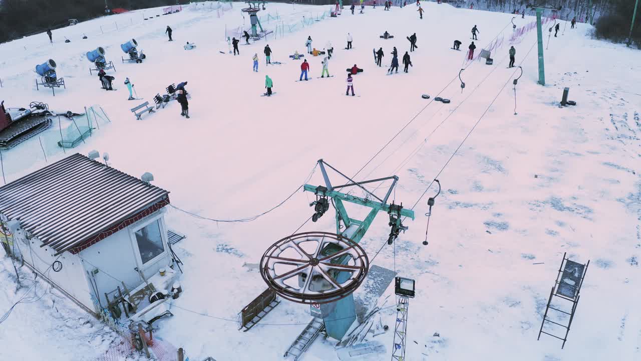 滑雪者和单板滑雪者在雪道上滑雪，滑雪缆车靠近滑雪缆车轮。视频素材