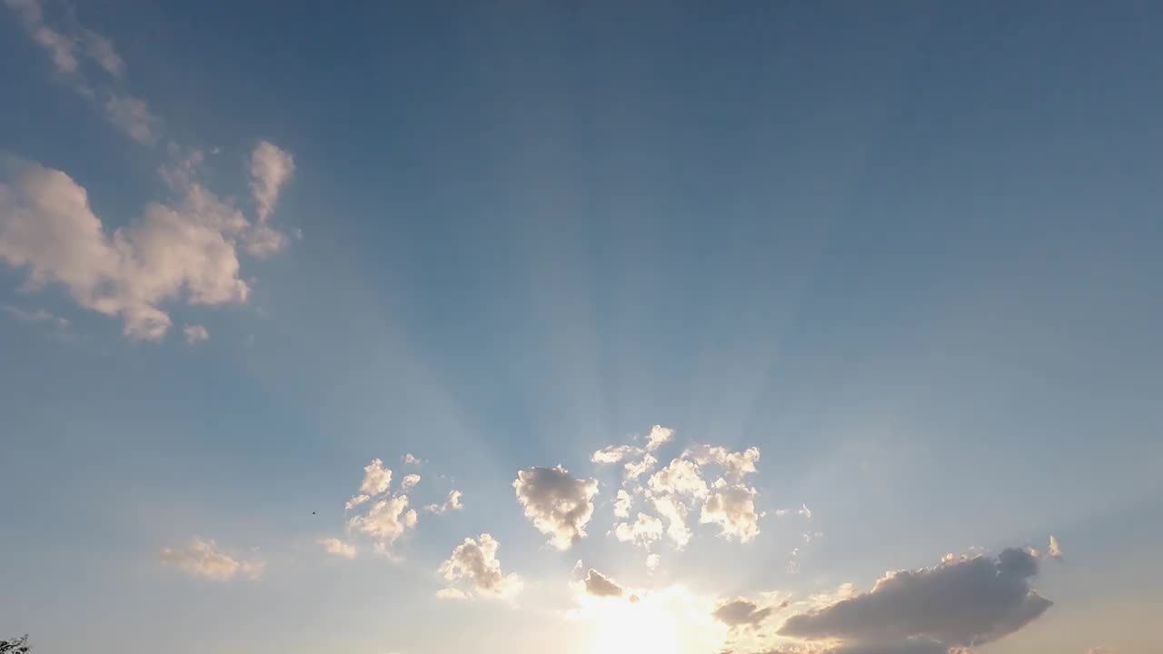 令人惊叹的太阳光线美丽的光束高在蓝色的天空。阳光透过云层，天空自然b卷镜头，4k分辨率的自然光。在夏季气候丰富多彩，空气清新的季节视频素材