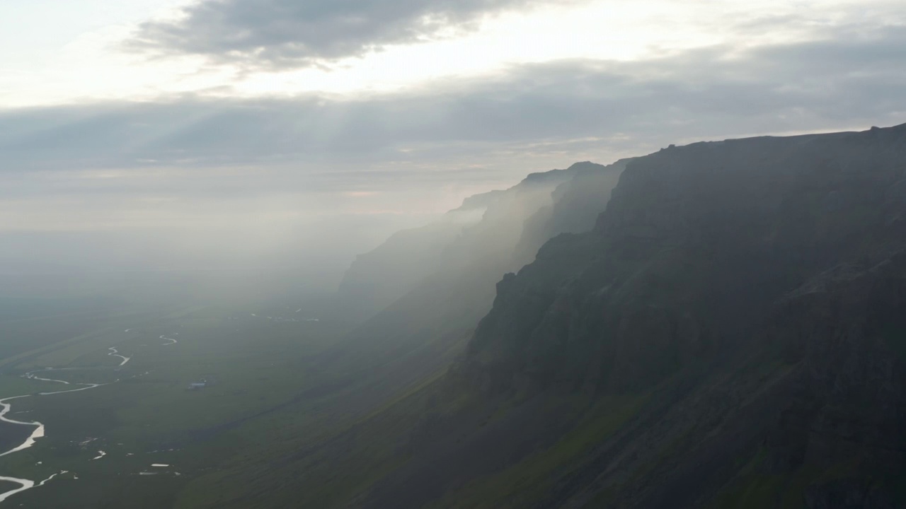 鸟瞰冰岛自然美景。飞近高山，阳光从乌云中穿过视频素材