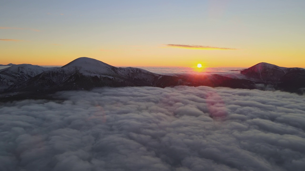 从空中俯瞰，充满活力的日出在白色浓密的云层上，远处的深色山脉在地平线上。视频素材