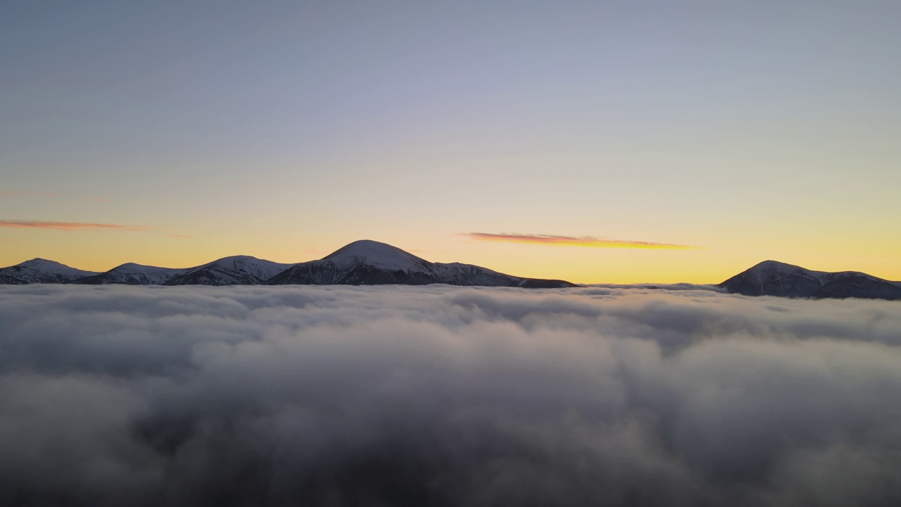 从空中俯瞰，充满活力的日出在白色浓密的云层上，远处的深色山脉在地平线上视频素材