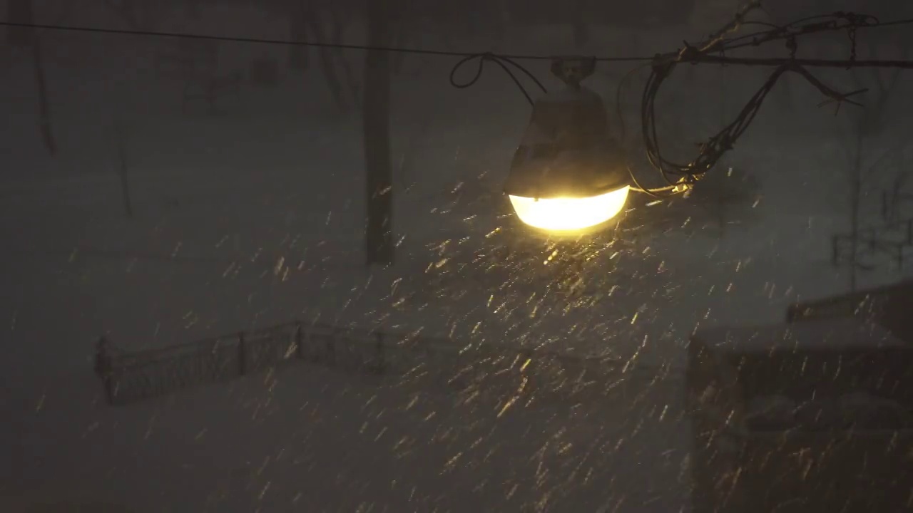 城市夜晚的雪花，街灯照亮的暴风雪，恶劣的天气，视频素材