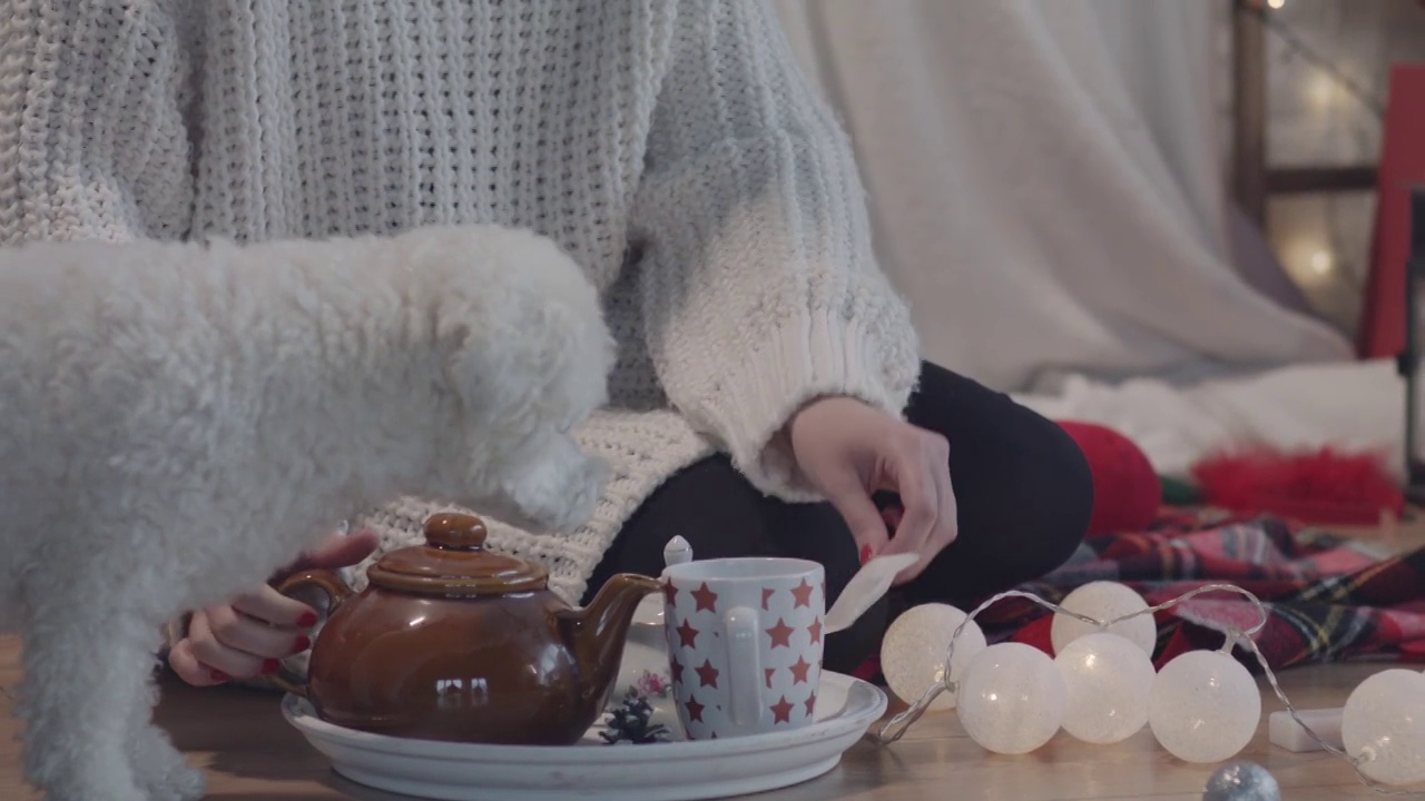 年轻女子坐在地板上，往杯子里倒热水，泡茶视频素材