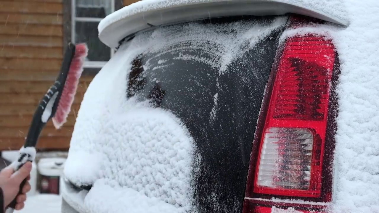 暴风雪过后，人们从车窗上刷下刚下的雪。在寒冷的冬天早晨，车主们的日常困难。汽车清洗窗户。冬天的季节。白色的雪。汽车护理。视频素材