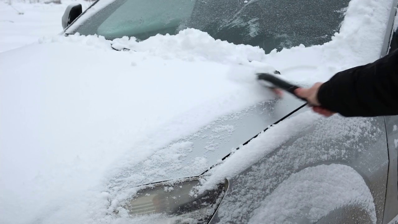 暴风雪过后，人们从车窗上刷下刚下的雪。在寒冷的冬天早晨，车主们的日常困难。汽车清洗窗户。冬天的季节。白色的雪。汽车护理。视频素材