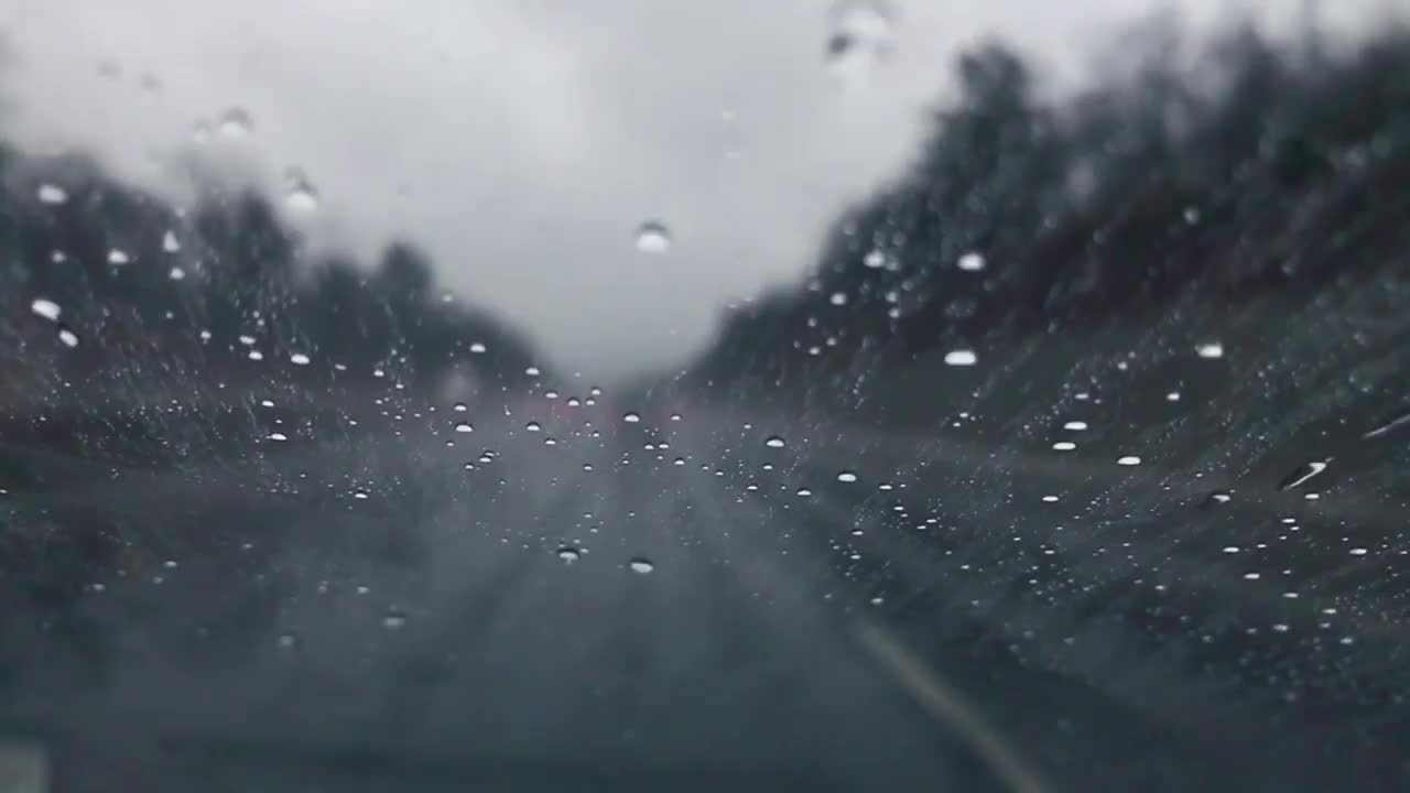 在下雨的时候开车，当雨滴向上移动汽车的后窗视频素材