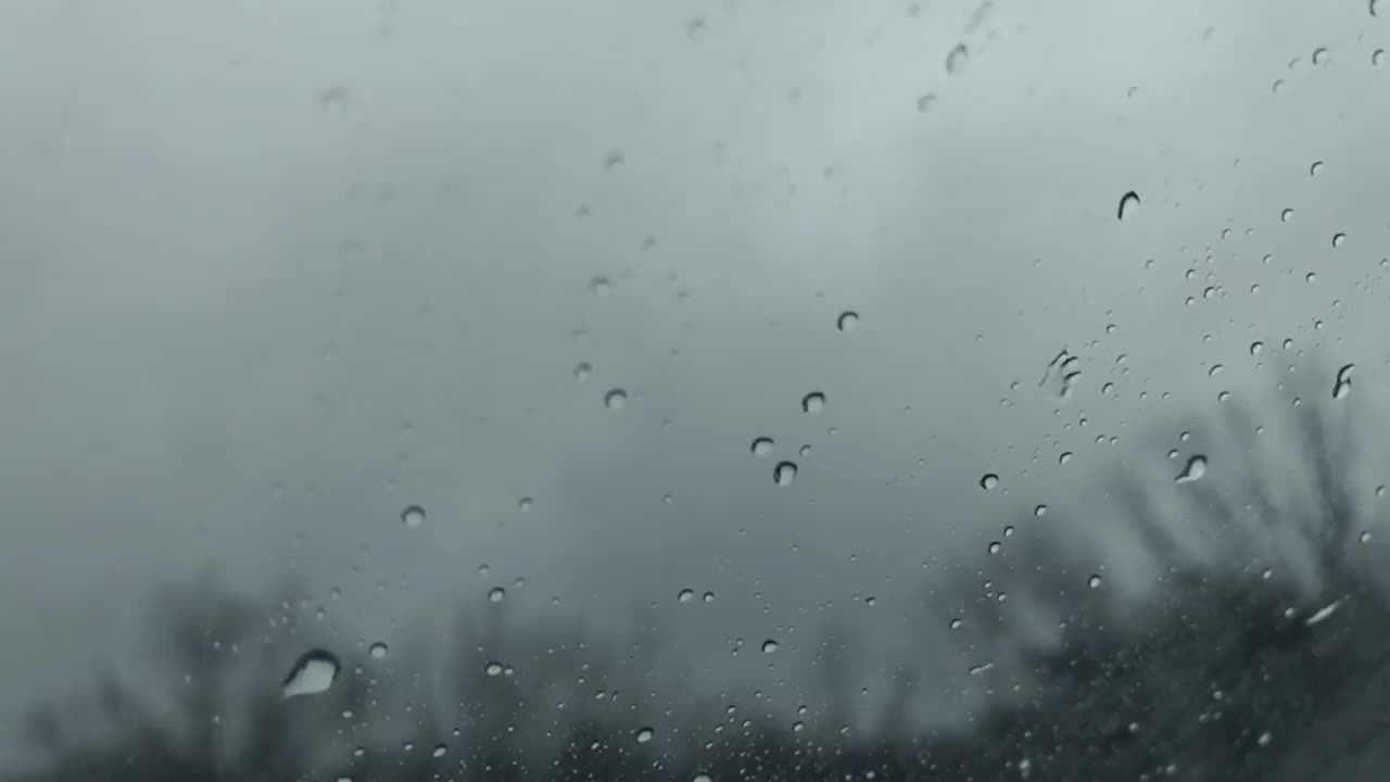 在下雨的时候开车，当雨滴向上移动汽车的后窗视频素材