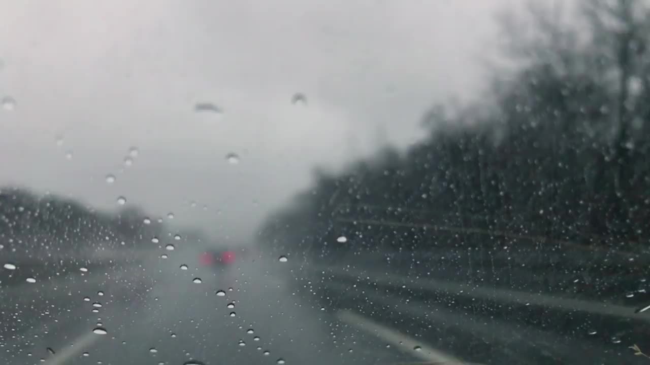 在下雨的时候开车，当雨滴向上移动汽车的后窗视频素材