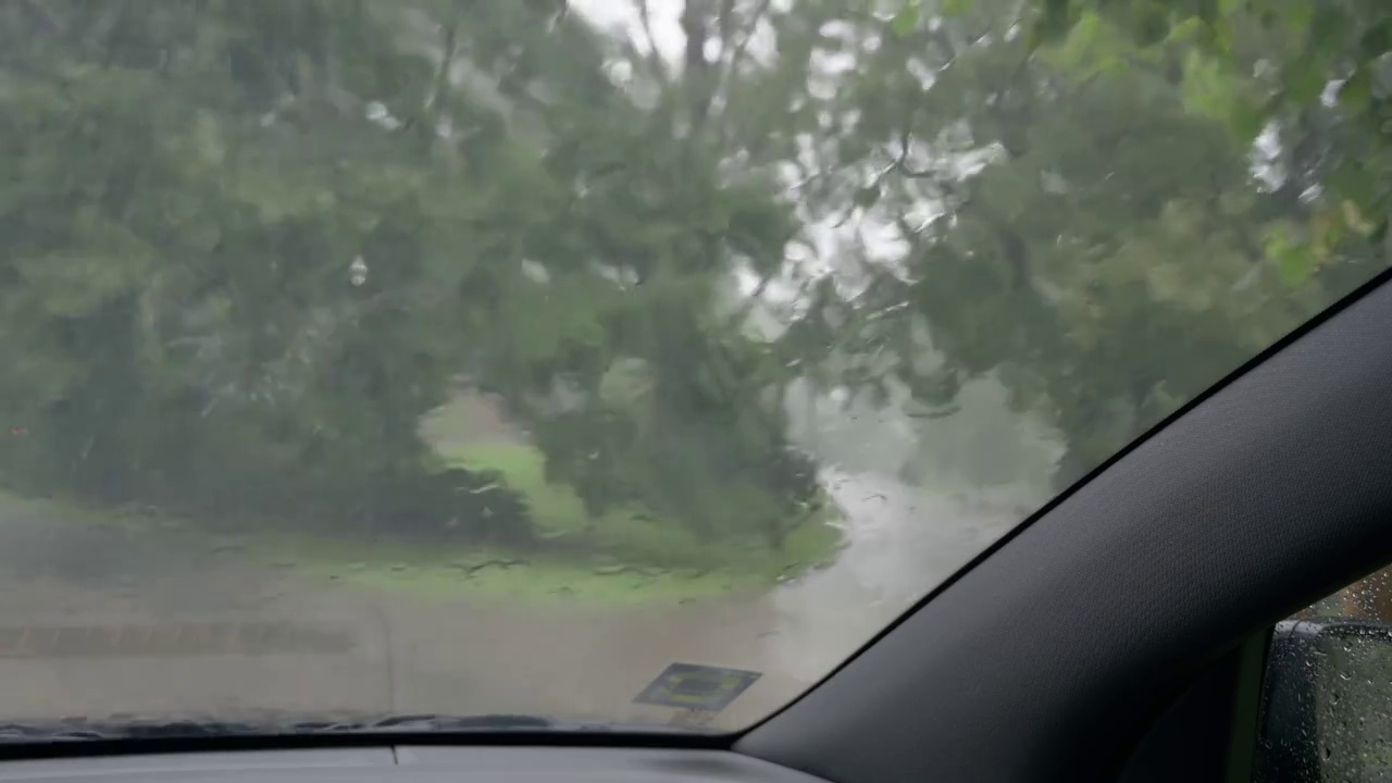 雨点沿着汽车的挡风玻璃流下来。从车里看到的雨。视频素材