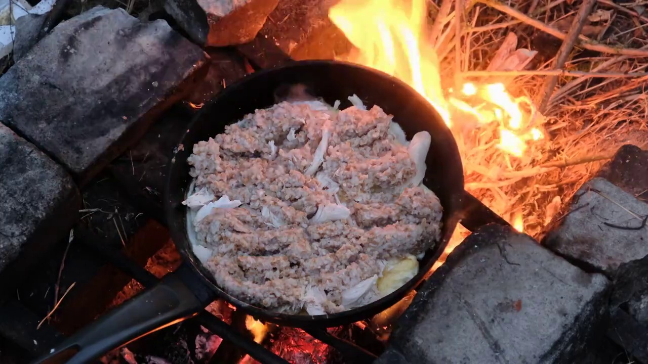 用鸡肉煮鸡蛋，用旅游营火煎锅煮粥，自然视频素材