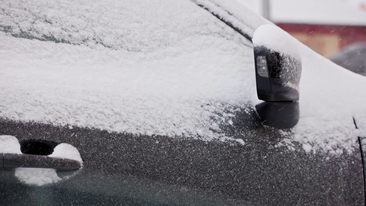 近距离的雪覆盖的汽车在冬季白天降雪，慢动作视频素材