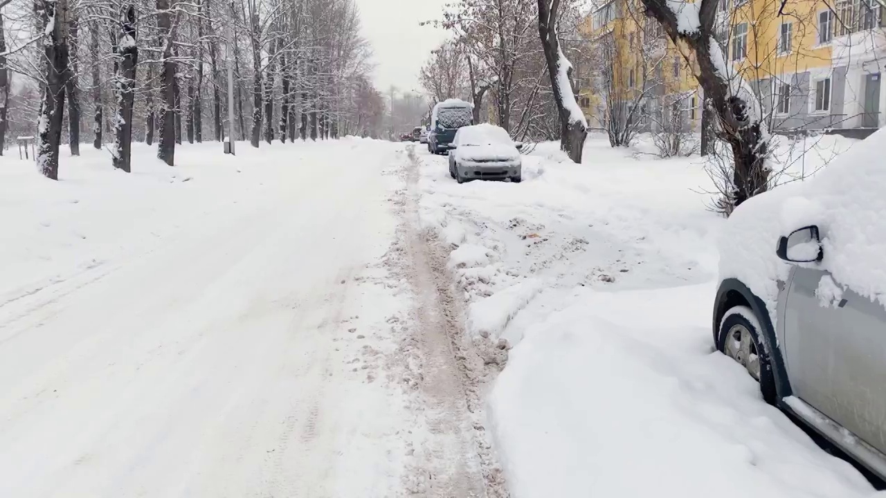 暴风雪后的极端降雪。停在黄色住宅楼附近的汽车被雪覆盖。视频素材