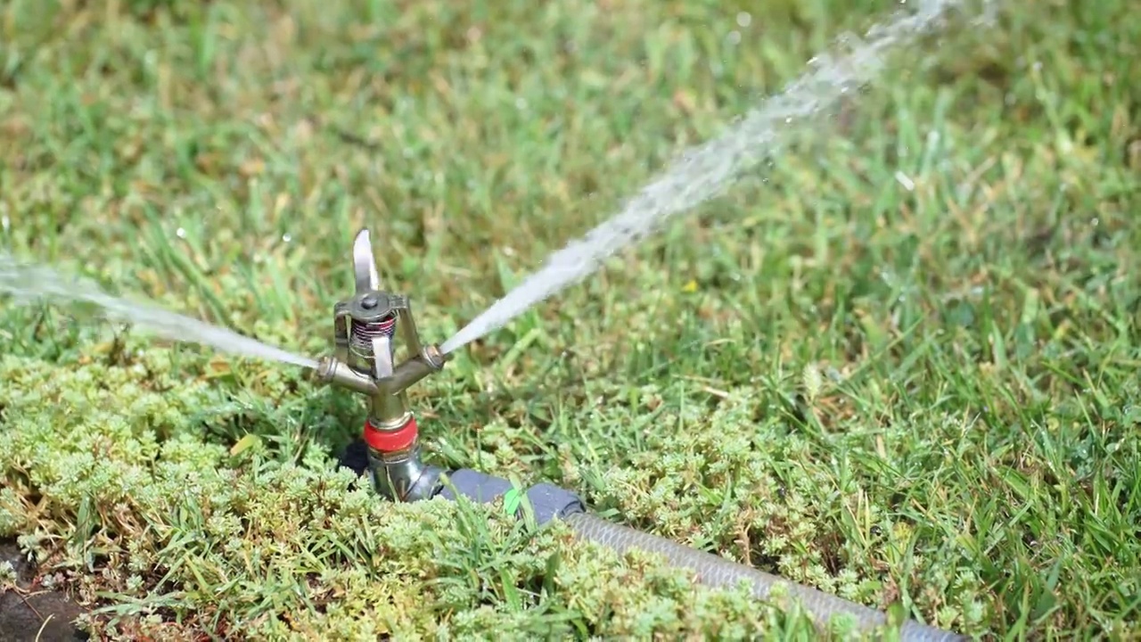 草坪自动洒水器，浇灌绿草。自动喷水灭火系统，慢动作视频素材