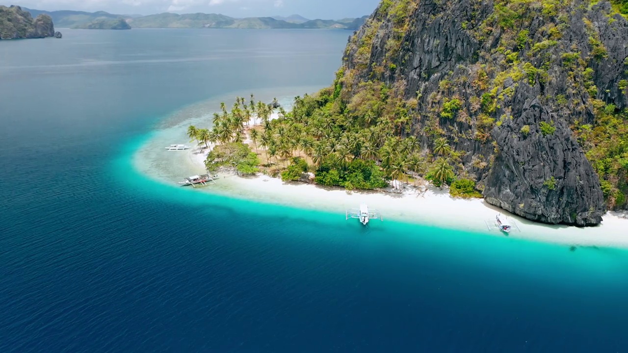 无人机拍摄的热带Ipil海滩，pinagbuutan岛，El Nido, Palawan，菲律宾。碧水、沙滩、棕榈树和游船——度假、旅游的旅游概念视频素材