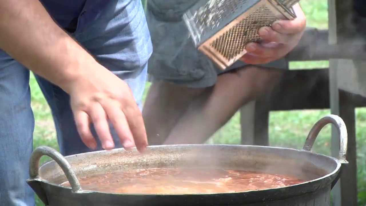 蒸汽从锅里冒出来，锅里煮着肉片和土豆，厨师正在磨碎大蒜来改善味道视频素材