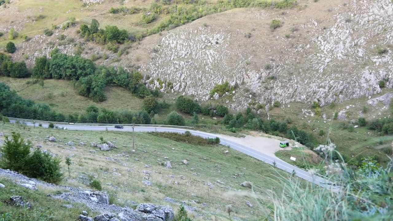 一辆黑色轿车在峡谷里一条河边的柏油路上高速行驶视频素材