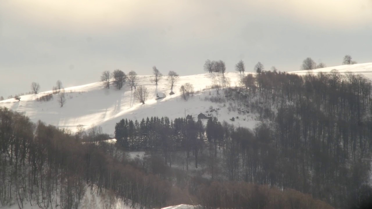 从邻近的山上看到白雪覆盖的山顶上孤立的小村庄，由于太阳光线使大气变暖而产生了视觉偏差视频素材