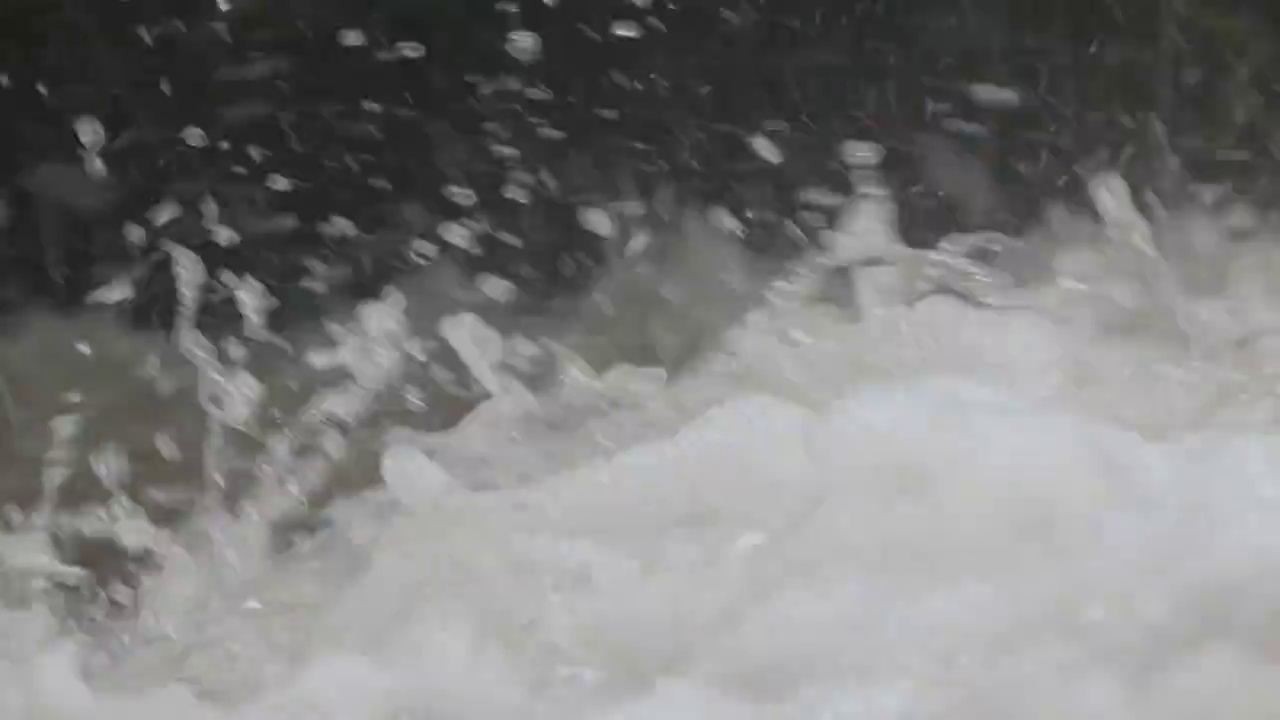 一场瓢泼大雨后，湍急的山河中溅起泡沫的水流跳过岩石视频素材