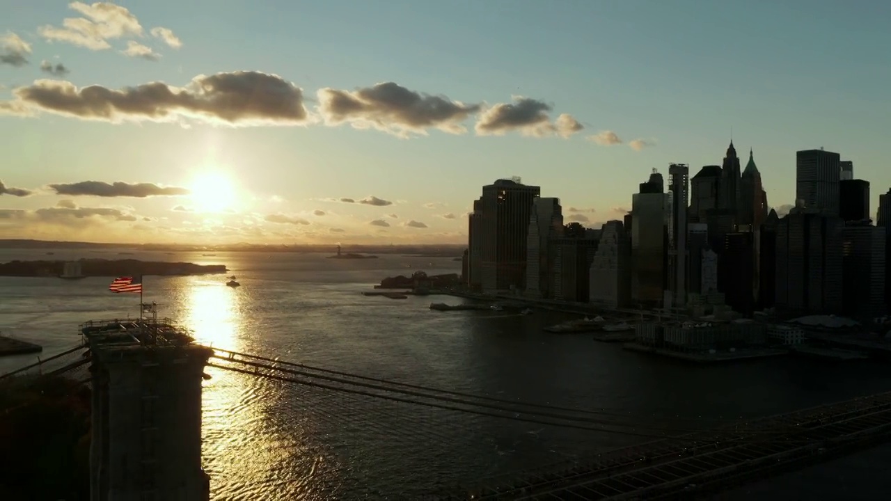 令人窒息的空中镜头，多彩的日落天空在水面上。布鲁克林大桥和市中心摩天大楼的剪影。曼哈顿，美国纽约市视频素材