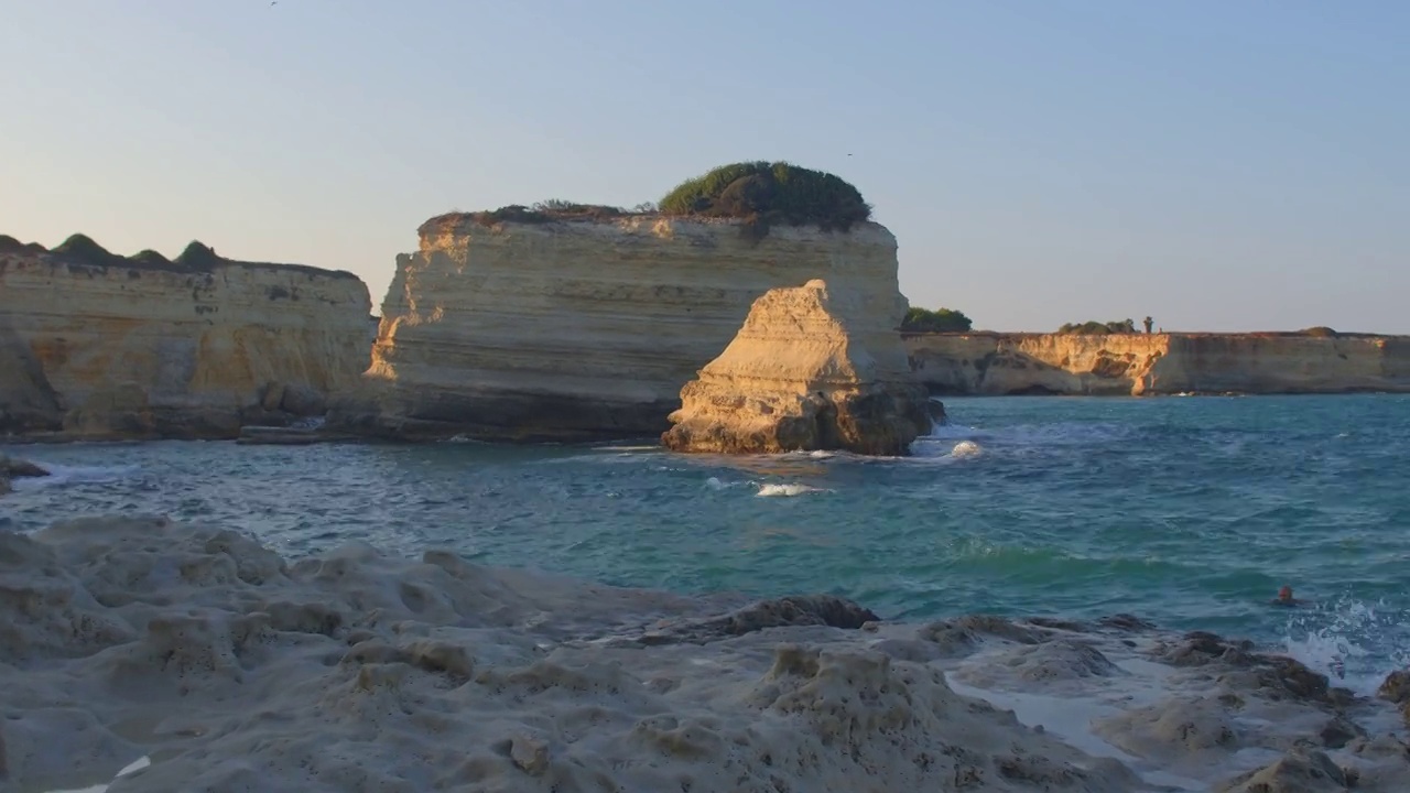 海岸多岩多石。海浪拍打着石头，太阳照亮了远处的石头视频素材