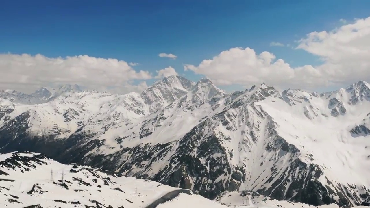 空中全景拍摄的冬季雪山山峰在一个明亮的阳光灿烂的日子视频素材