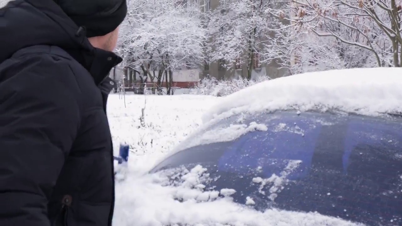 冬天，戴着黑色皮手套的司机用刷子擦车窗上的雪。视频素材