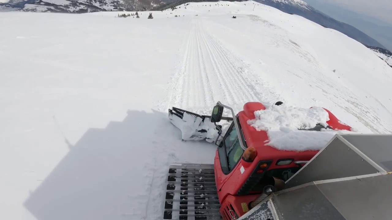 雪车滑道和扫雪机准备雪道，在滑雪场的深厚雪道中行驶。重型机械运输山顶自由滑雪者视频素材