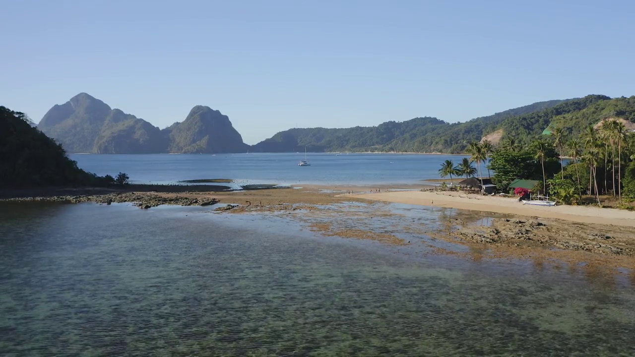 4k鸟瞰图Cas Cabanas, El Nido，巴拉望，菲律宾。退潮时在热带沙滩上漫步的游客。背景是山脊视频素材