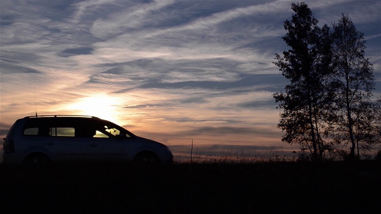 汽车在黄昏时分行驶在乡间小路上，身后扬起一阵尘土视频素材