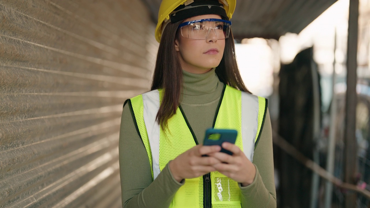 年轻的西班牙裔女建筑师在建筑工地使用智能手机视频素材