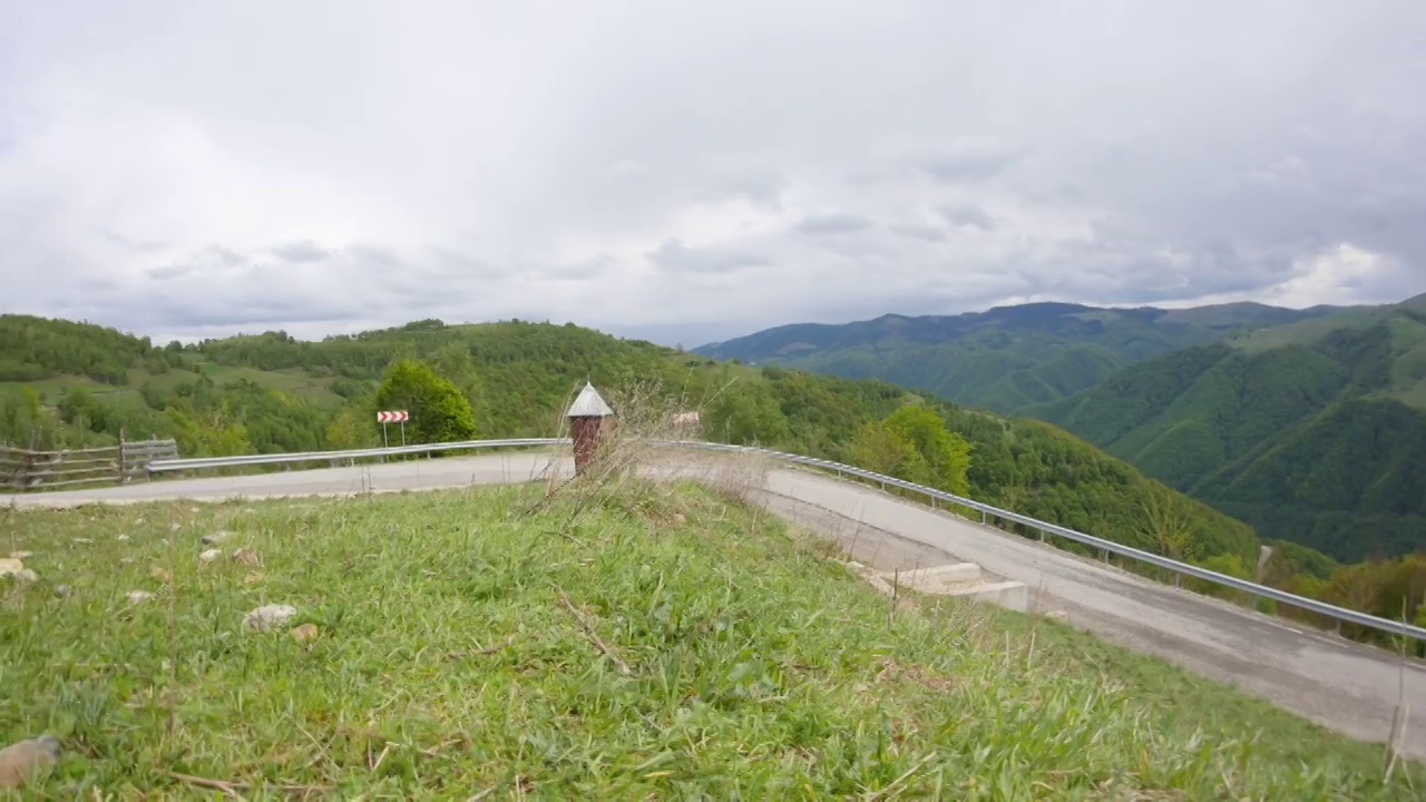 云朵在茂密的高山上飞驰，在蜿蜒向下延伸的道路上飞驰视频素材