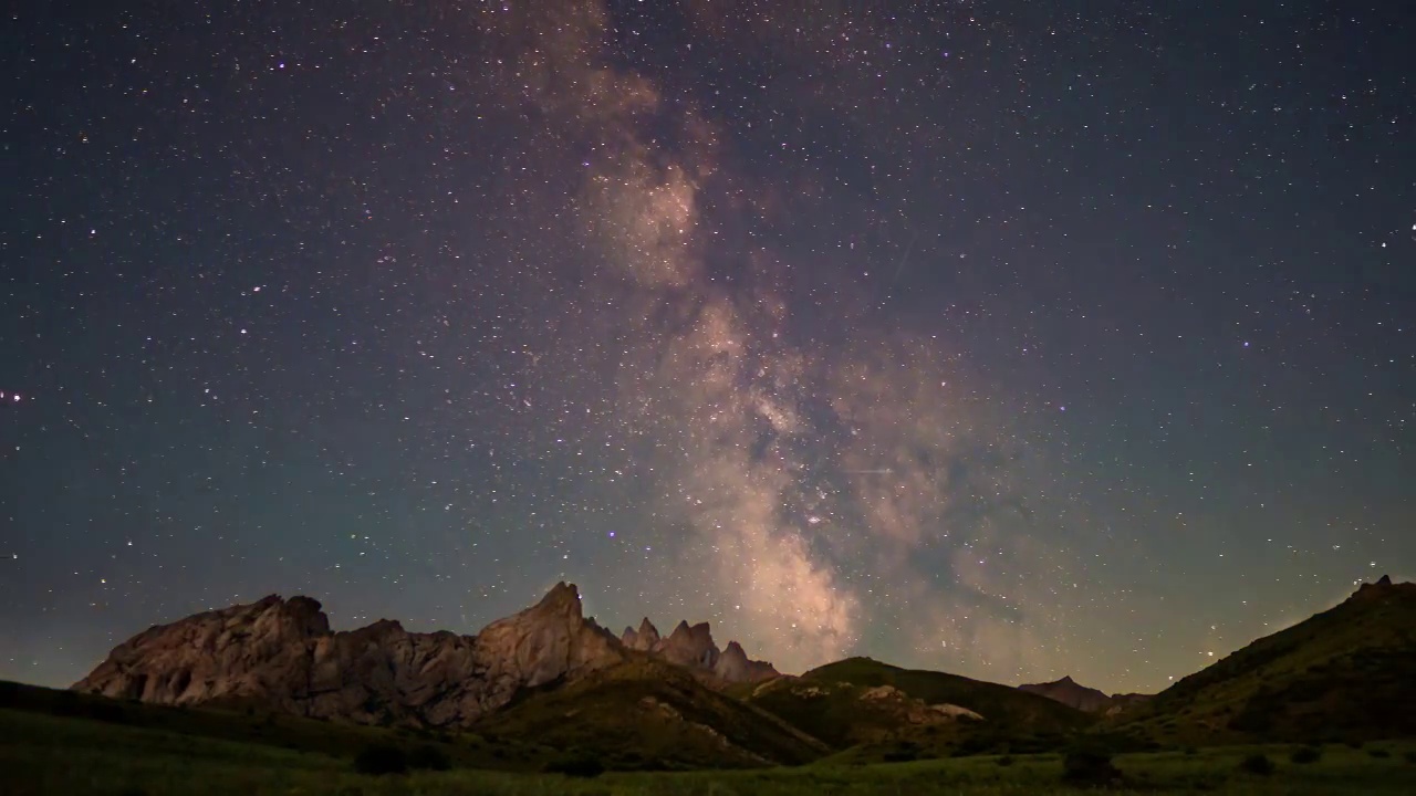 在群山的衬托下，银河在夜空中运动。视频下载