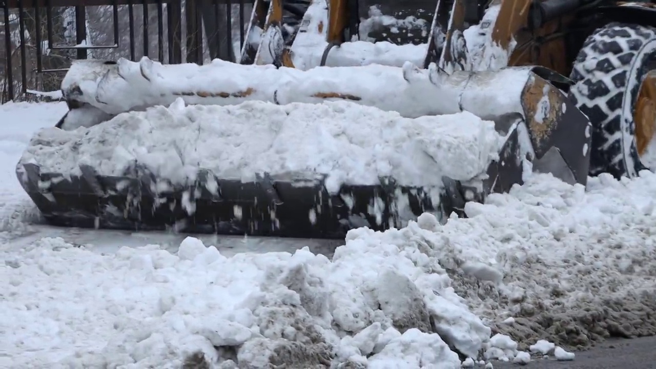 挖掘机，一辆汽车在清理城市街道上的积雪视频下载