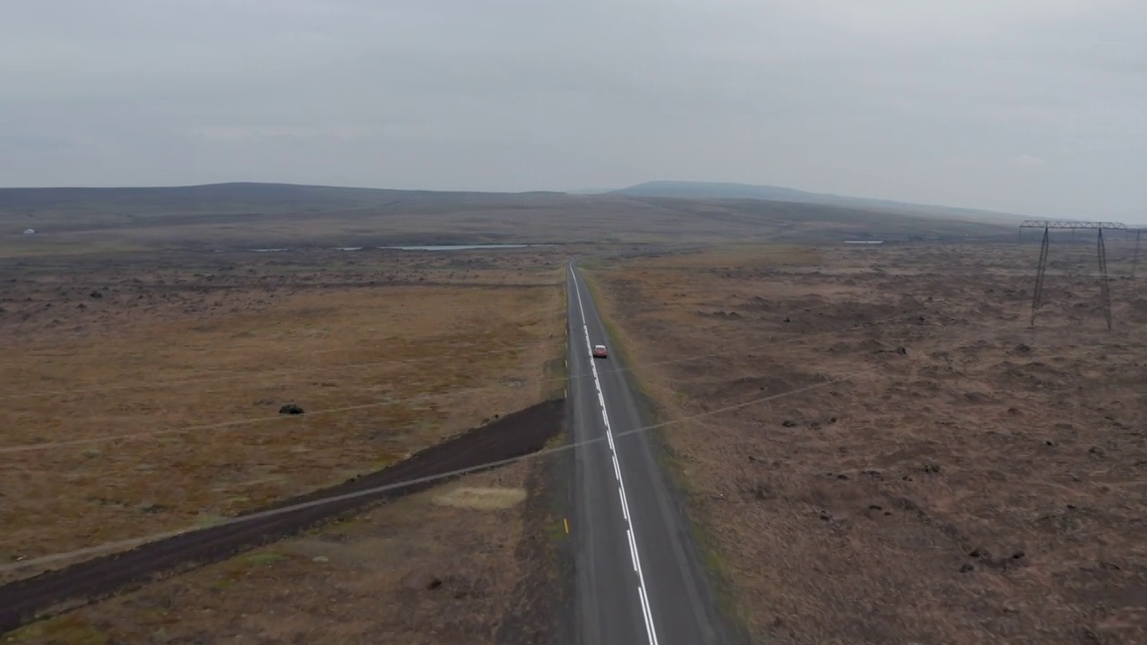 无人机观看在冰岛野外乡村高速公路上行驶的4x4汽车。高角度看冰岛雄伟的苔藓高原与汽车驾驶环路，冰岛最重要的高速公路视频素材