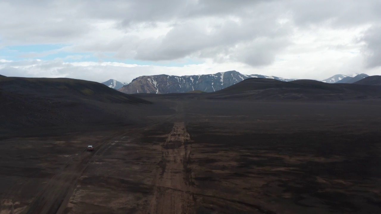 鸟瞰斯卡夫塔费尔国家公园里的拉卡加黑色火山沙漠，汽车扬起尘土，驶离公路。无人机视图4 × 4汽车驾驶土路探索冰岛高地视频素材