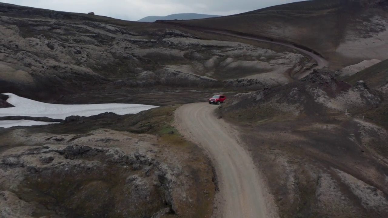 鸟瞰图4 × 4汽车行驶在蜿蜒的道路上，探索冰岛高地的荒野。无人机查看越野车在冰岛乡村的土路旅行。冒险和发现视频素材