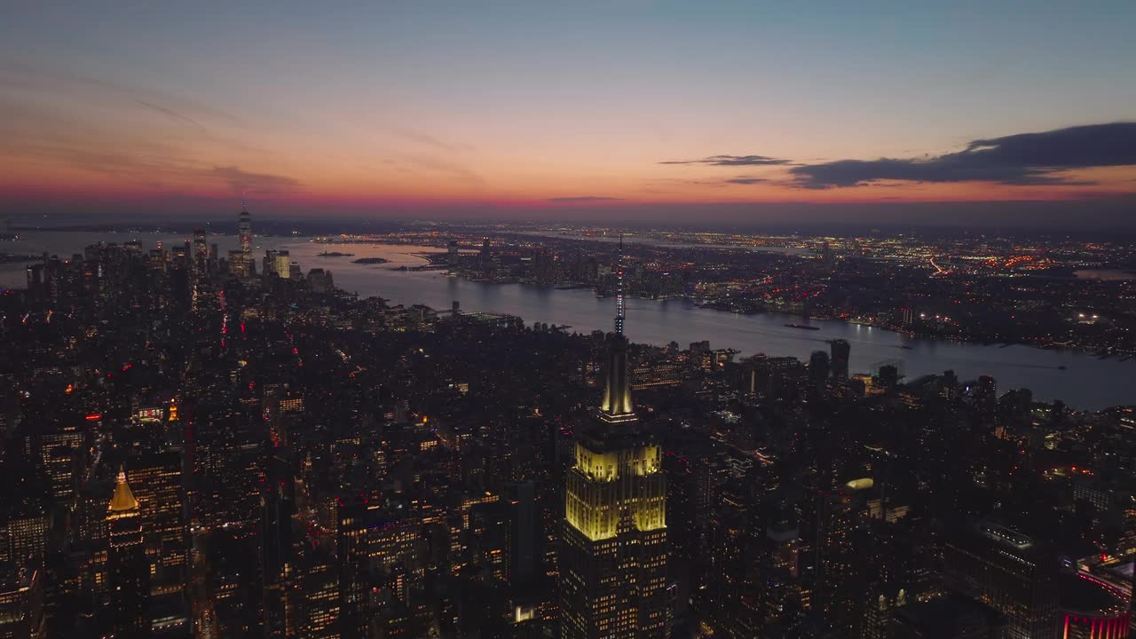 大城市黄昏时的空中全景。向下倾斜至帝国大厦顶部灯光闪烁的装饰。曼哈顿，美国纽约市视频素材