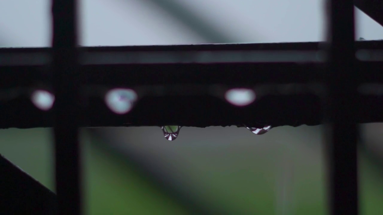 雨滴从窗户的金属管中落下的特写慢动作镜头。季风的背景视频素材