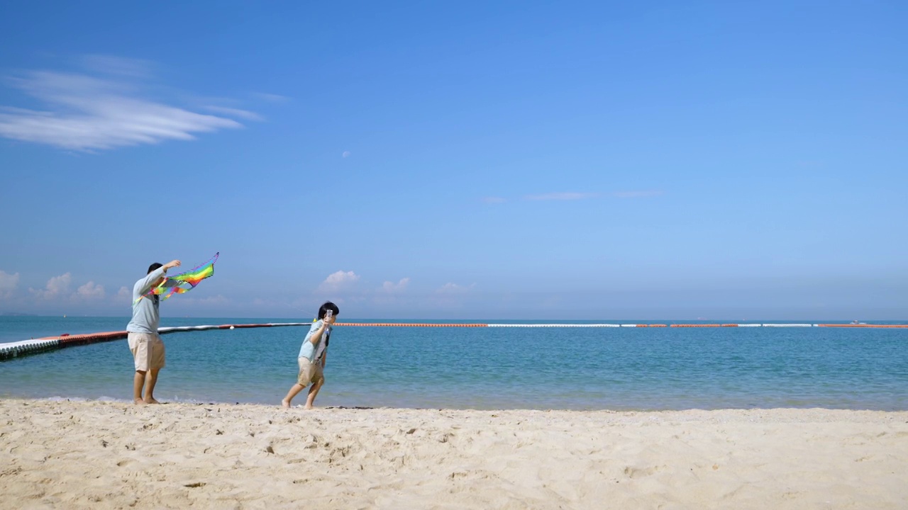 亚洲父子俩跑着去接风筝在空中飞翔，他们在周末、假日活动、旅游、休闲、亲子关系中嬉戏视频素材