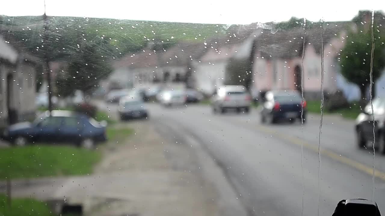 雨滴滴落在卡车的挡风玻璃上，卡车可以看到路面以外行驶的汽车视频素材