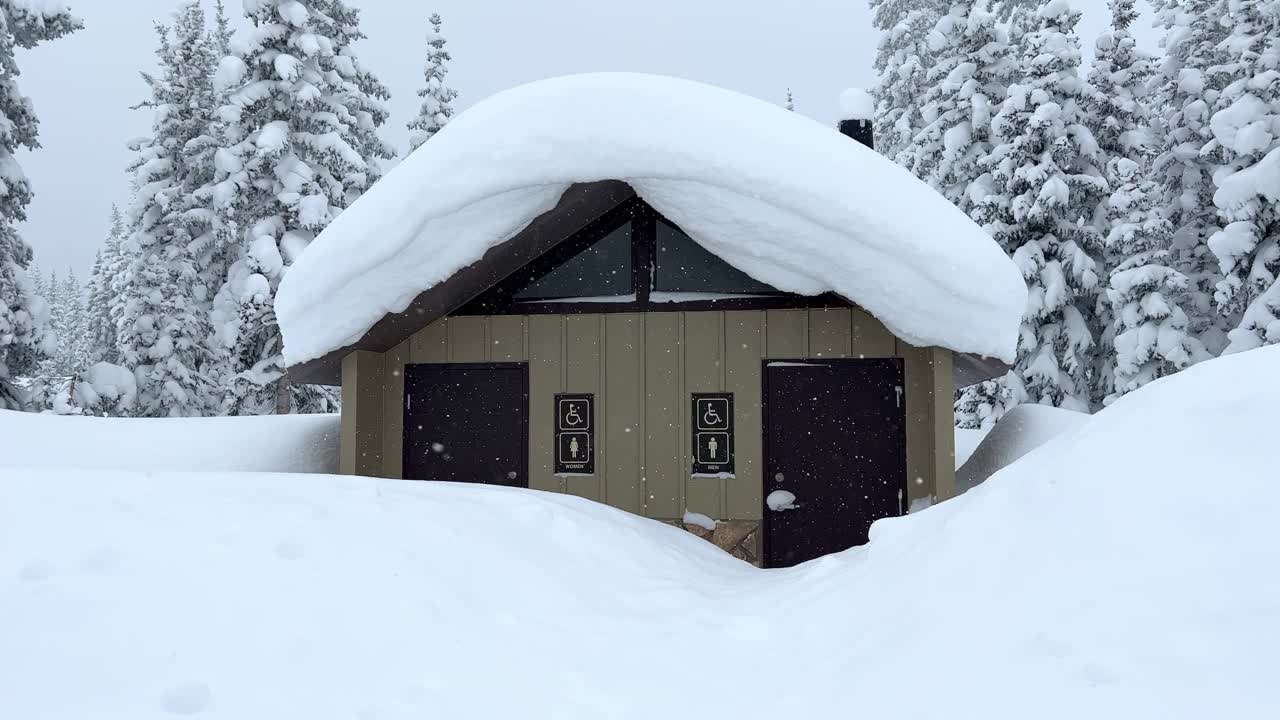 在冬天，树木被雪覆盖，雪花飘落，休息站的洗手间视频下载