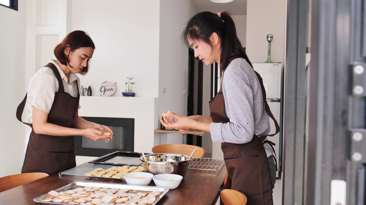 两个年轻的亚洲青少年愉快地使用烘焙材料在她的家庭厨房。采购产品面包房，羊角面包，食品，小型，商业，厨师，烹饪，一个人。视频素材