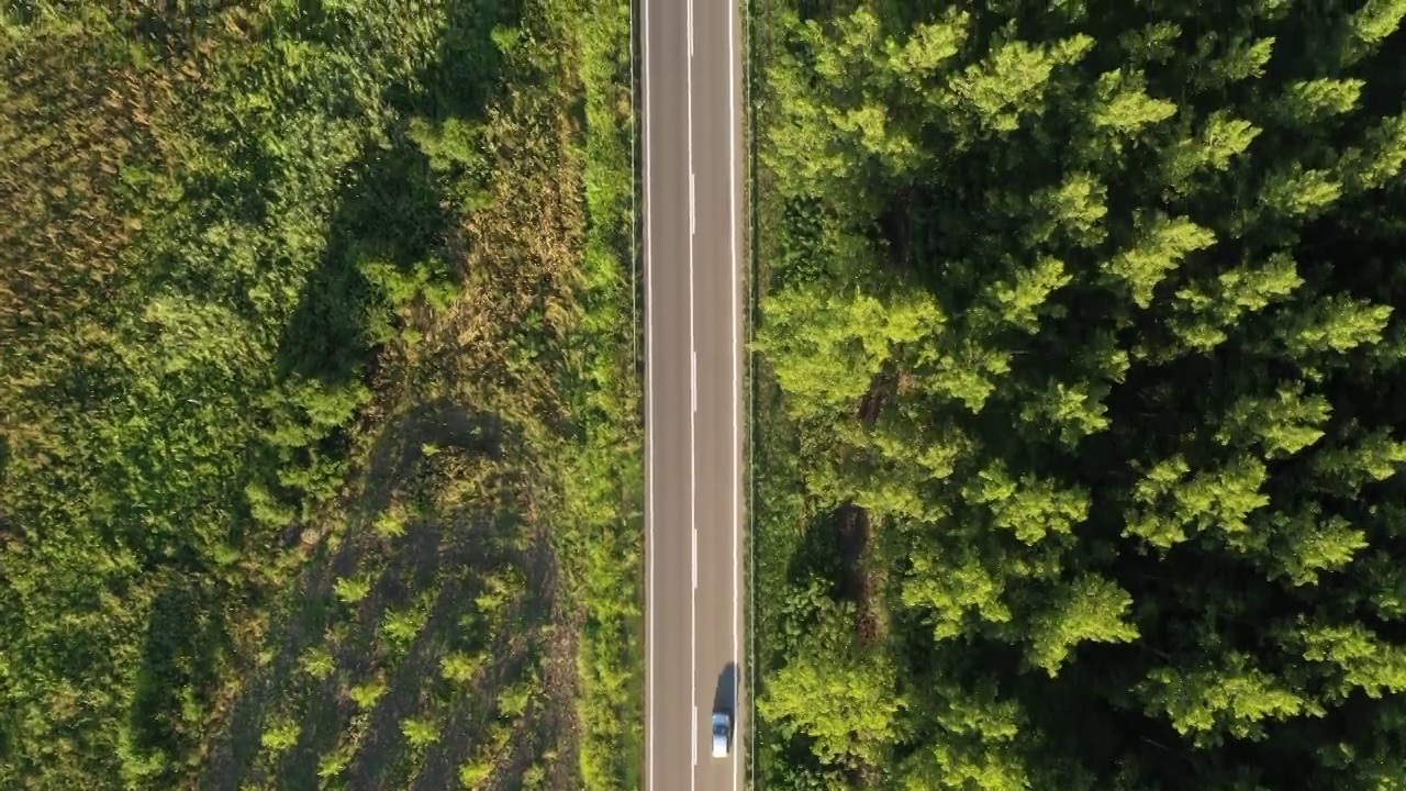 无人机拍摄的两辆车在绿色的乡村风景道路上擦肩而过视频素材