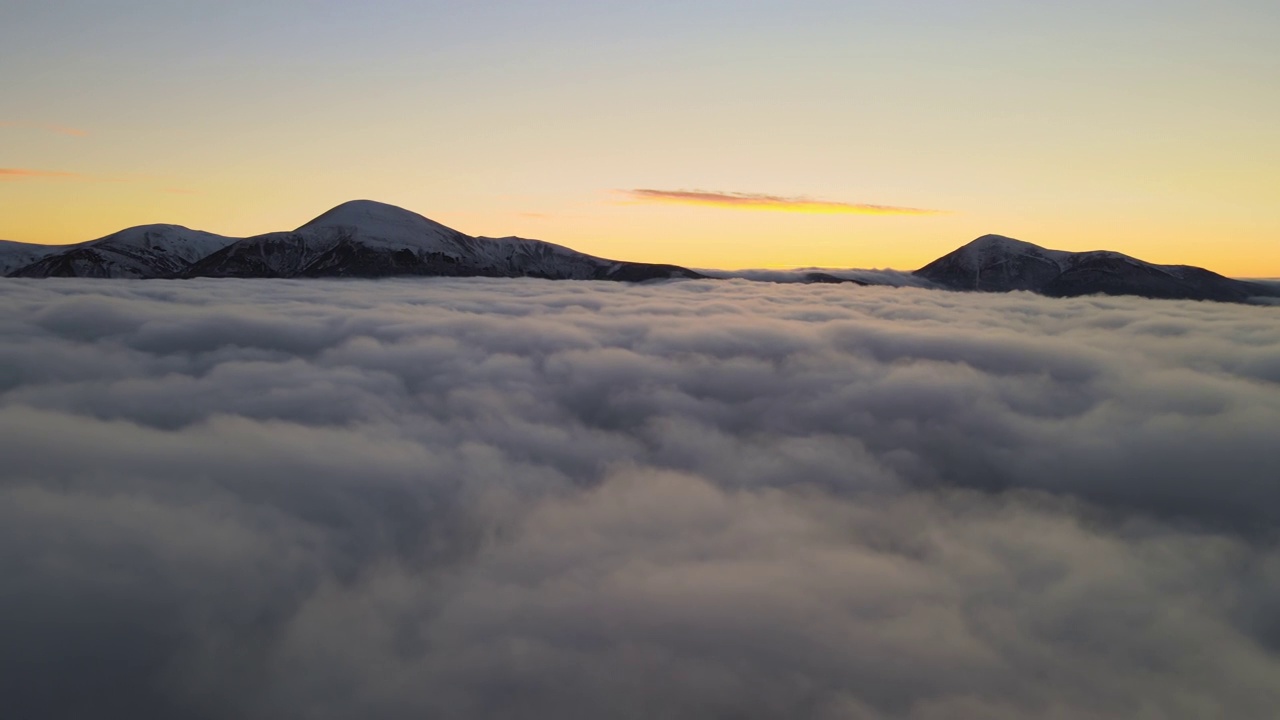 从空中俯瞰，在白色浓雾中充满活力的日出，地平线上是遥远的喀尔巴阡山脉的深色山峰视频素材