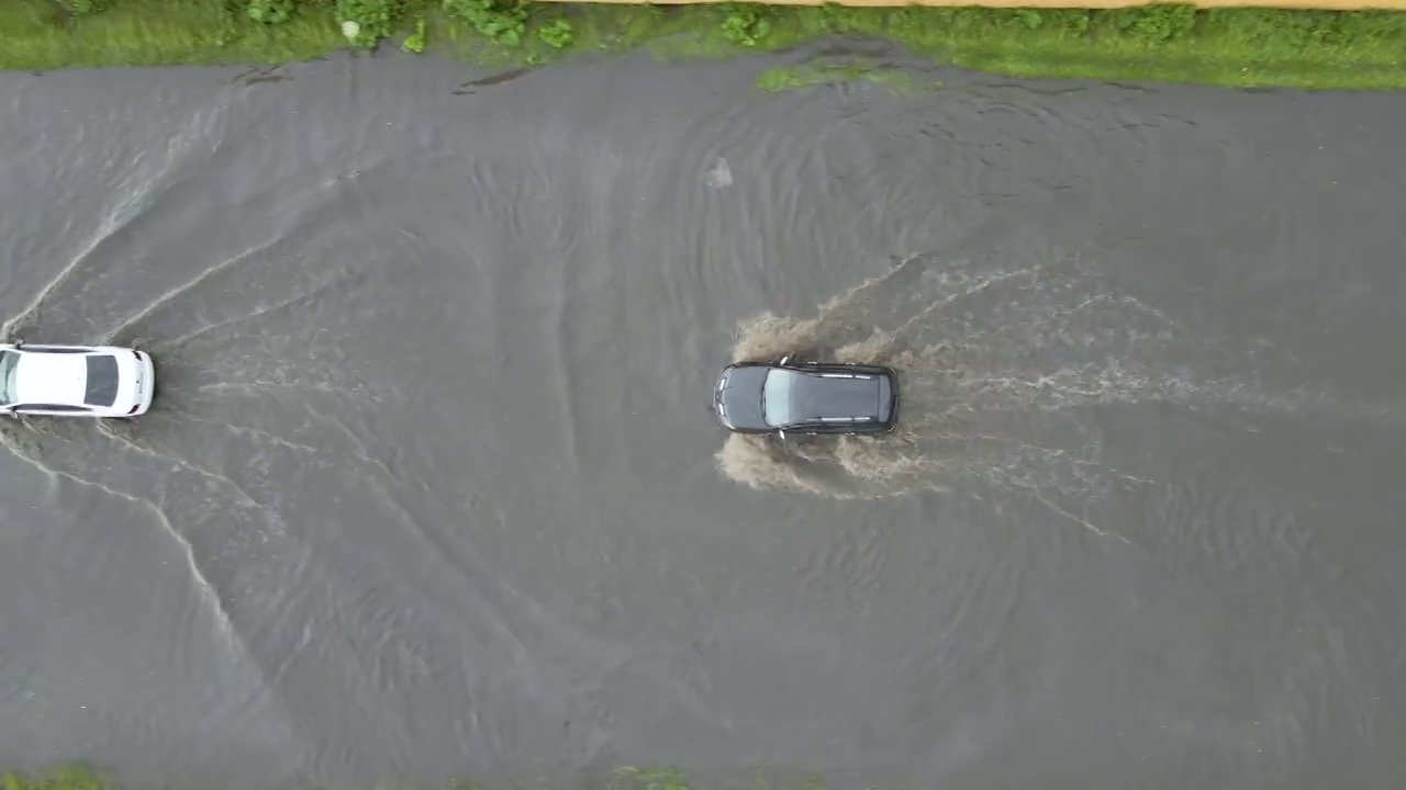 城市交通鸟瞰图，汽车行驶在暴雨后被淹没的街道上。道路排水系统的问题视频素材