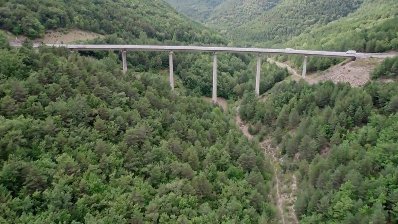 一座桥，一座现代的高架桥，建在山上，有一条三车道的柏油路。钢筋混凝土码头结构的桥梁连接着山林中的两座小山。视频素材