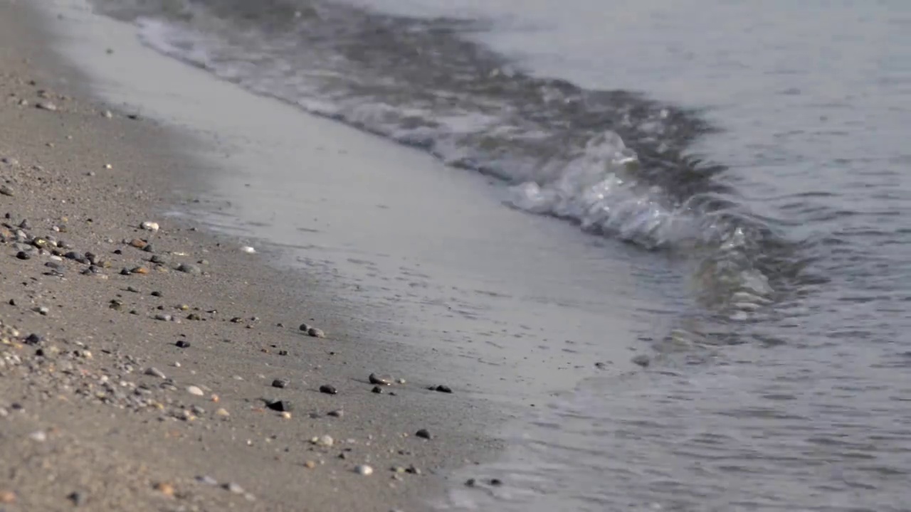 海浪拍打着沙滩上的细沙和鹅卵石视频素材