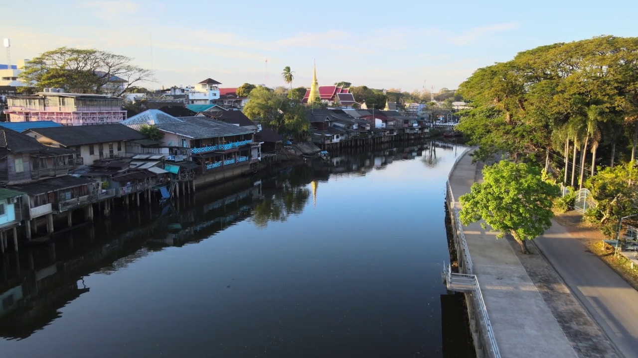 Chanthaboon滨水区(Aerial-Drone VDO) -泰国寺庙和古老的木制房屋，日落时沿着河岸的游船旅行。视频素材